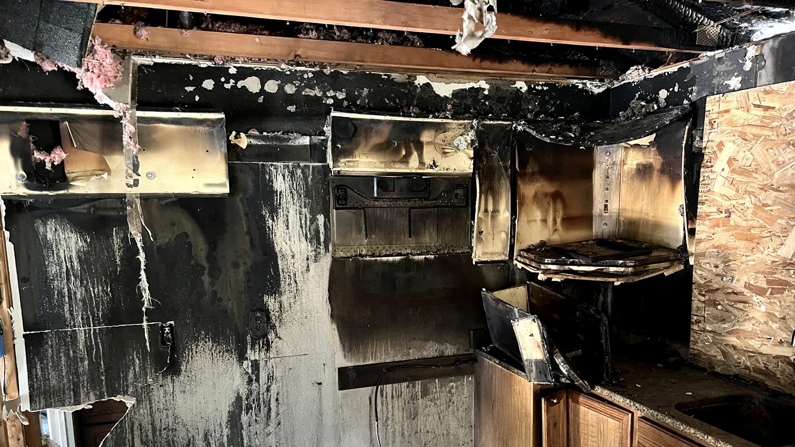 Fire-damaged kitchen interior with soot-coated walls awaiting restoration.